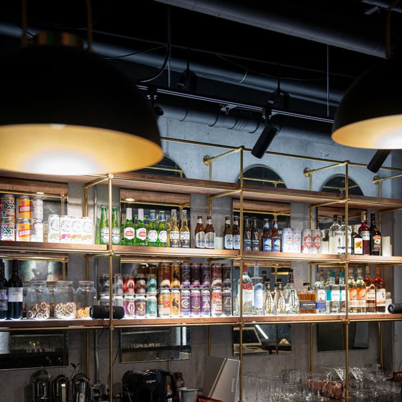 The back bar, stocked shelves under brass pendants