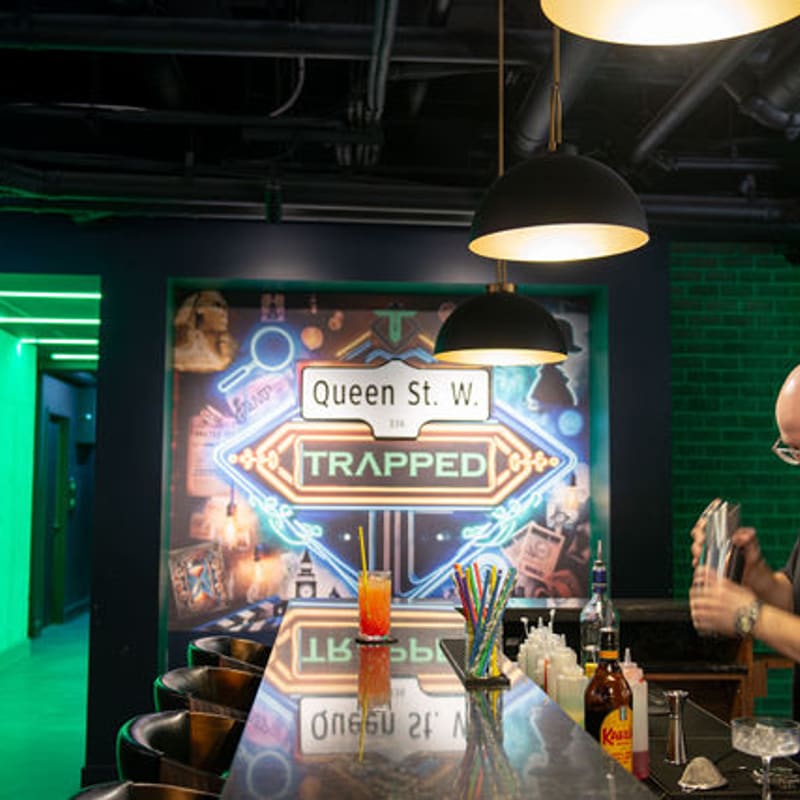 A bartender mixing a drink under the Queen St. W. neon