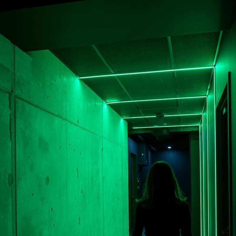 A guest walking the neon-green corridor toward the rooms